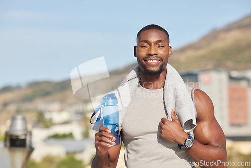 Image of Portrait, fitness and water bottle with a sports black man or runner standing outdoor with a towel during exercise. Training, running and workout with a young male athlete outside for cardio