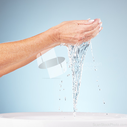 Image of Senior hands, water and splash for clean hygiene, fresh minerals or wash against a studio background. Hand of elderly holding natural liquid for skin hydration, wellness or skincare in sink or basin