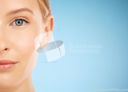 Image of Skincare, beauty and half portrait of a woman for dermatology isolated on a blue background. Makeup, wellness and face of a model for cosmetics, health and collagen with mockup space on a backdrop