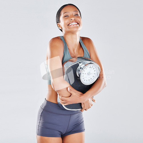 Image of Diet, weightloss and scale with a black woman athlete in studio on a gray background for body positivity or health. Fitness, weightscale and losing weight with a young female posing for wellness