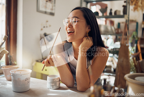 Image of Happy creative asian woman, art and smile for pottery small business startup in ceramic design. Artistic Japanese female smiling in happiness for arts and crafts holding paint brush for creativity