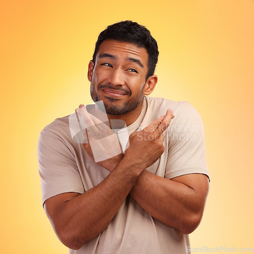 Image of Fingers crossed, man and model with a orange studio background with hand sign for luck. Smile, hope and faith of a person with beard holding hands gesture for wish and optimism feeling hopeful