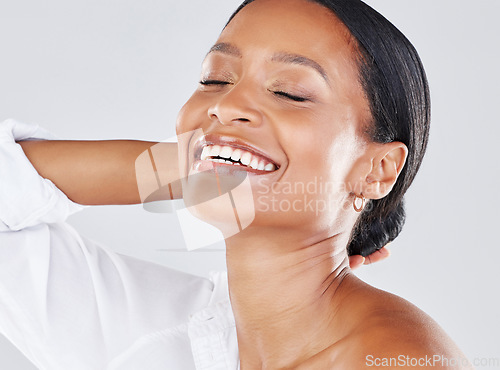 Image of Face, happy and smile with a model black woman in studio on a gray background for freedom or expression. Wellness, beauty and cosmetics with an attractive young female laughing or joking indoor