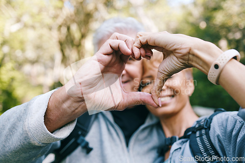 Image of Heart, love hands and senior couple outdoors on vacation, holiday or hiking trip. Affection sign, romance emoji and elderly interracial couple, man and woman bonding together in nature on a hike.