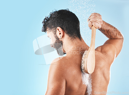 Image of Shower, man and soap for body cleaning with brush in blue background studio, grooming hygiene and skincare wellness. Model, water and luxury spa body care, dermatology and self care morning routine