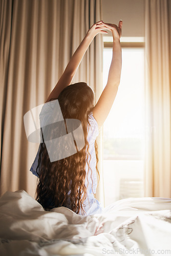 Image of Morning, wake up and a woman stretching in the bedroom of her home after sleeping or rest on the weekend. Back, bright and flare with a female sitting on a bed while waking with an early stretch