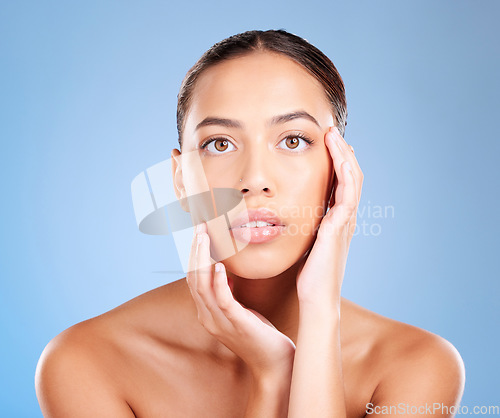 Image of Face portrait, skincare and beauty of woman in studio on a blue background. Hands, natural cosmetics and makeup of young female model with healthy, smooth and glowing skin after facial treatment.