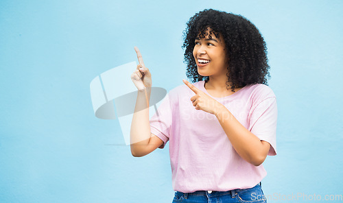 Image of Mock up, studio and happy black woman point at sales promo, discount gift deal or mockup space. Female advertising gesture, marketing product placement and African model isolated on blue background