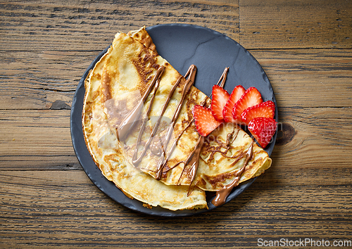 Image of plate of crepes with strawberry and melted chocolate sauce