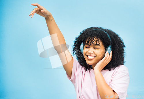 Image of Dance music, studio mock up and black woman listening to song, audio podcast or radio sound for energy, relief or fun. Studio mockup, dancing girl and African girl isolated on blue background wall