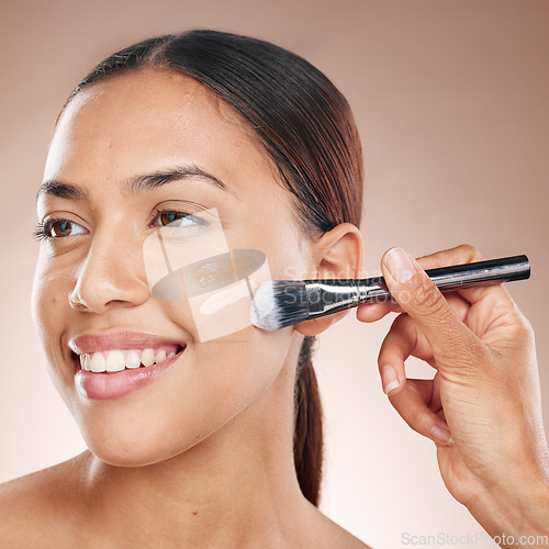 Image of Beauty, makeup and woman with foundation in a studio for cosmetic skincare routine with a brush. Cosmetics, skin and happy girl model from Mexico with a luxury face tone isolated by brown background.