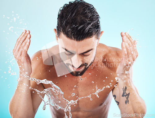 Image of Skincare, water splash and man in a studio for a wellness, health and self care body routine. Cosmetics, hydration and male model with natural dermatology facial treatment isolated by blue background