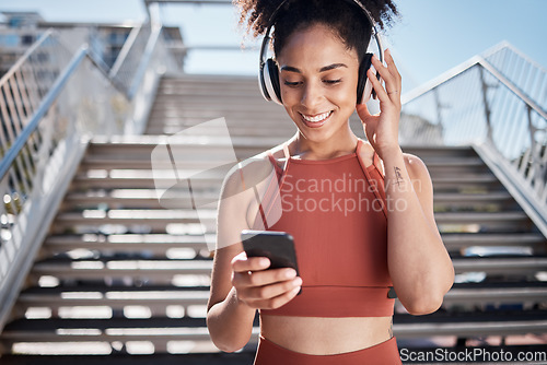 Image of Fitness, music headphones and black woman with phone for social media in city. Sports, exercise and female athlete streaming song, radio or podcast on 5g mobile smartphone after training outdoors.