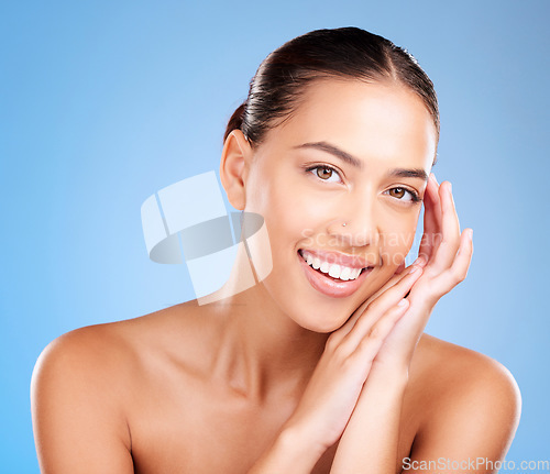 Image of Woman, skincare and studio portrait with smile, happy and natural glow from cosmetics, self care or hands. Model, cosmetic beauty and self love with makeup aesthetic, shine or face by blue background