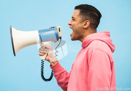 Image of Man, speaker and megaphone in studio for justice, microphone speech and communication in blue background. Male shouting, protest announcement and audio information with voice broadcast for change