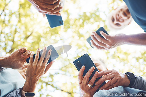 Image of Fitness, group with smartphone in hands and running in park, technology low angle and check exercise mobile app. Elderly runner team outdoor with health, senior and phone for cardio sports motivation