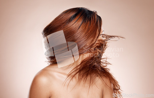 Image of Hair care, wind and woman with shine, natural beauty or cosmetics on studio background. Female, girl or salon treatment for healthy hair, luxury or wellness for growth, flip or hairstyle with keratin