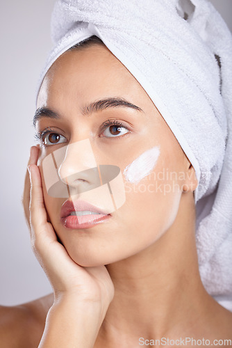 Image of Woman, head towel and cream for skincare, wellness and organic facial for face detox on grey studio background. Female, lady or makeup for natural beauty, confident and cosmetics for grooming routine