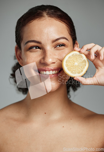 Image of Skincare, face and woman with lemon in studio isolated on a gray background. Fruit, organic cosmetics and happy female model holding fruits for healthy diet, vitamin c or minerals, wellness or beauty