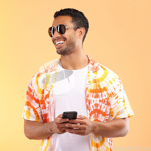 Image of Sunglasses, phone and man typing in studio isolated on a yellow background. Technology, thinking and happy male model with mobile smartphone for social media, text messaging or internet browsing.
