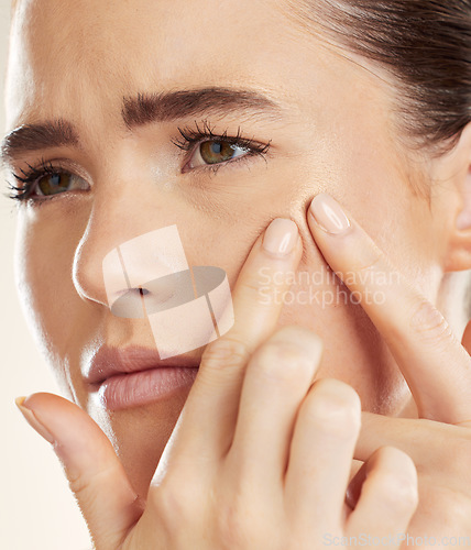 Image of Face, hands and pimple with a woman checking or examining her skin for acne problems in studio. Facial, fingers and breakout with an attractive young female indoor to squeeze or pop a blackhead