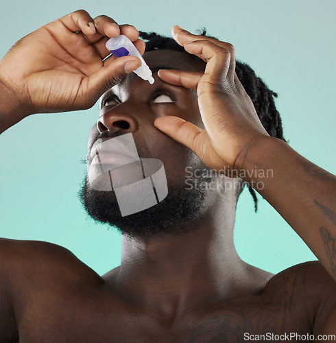 Image of Black man, studio and eye drop for health vision, wellness and self care by blue backdrop for morning routine. African gen z model, eyes and product for healthcare, medicine and medical serum bottle