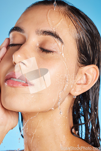 Image of Woman, shower water and face for beauty, skincare and peace with blue studio background. Calm, relax and healthy young person doing morning self face for skin glow with clean beauty treatment