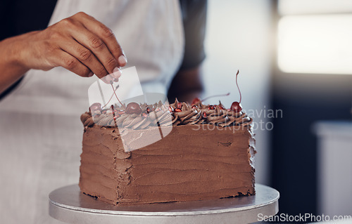 Image of Hand, cake and food with a man chef working in a kitchen while preparing dessert for a party celebration. Cooking, chocolate and cherries with a male at work in a bakery to make gourmet confectionary