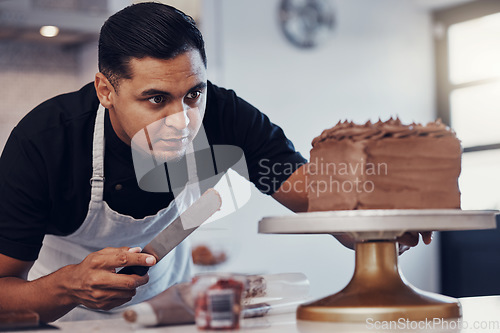 Image of Baking, kitchen and man icing cake with chocolate frosting and piping bag in bakery with focus and skill. Sweets, small business and baker decorating dessert for birthday event and working from home.