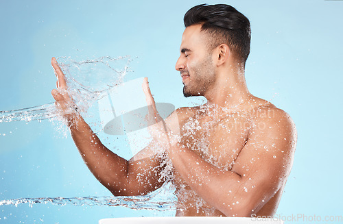 Image of Body, water splash and skincare of man cleaning in studio isolated on a blue background. Hygiene, water drops and male model washing, bathing or grooming for healthy skin, facial wellness or beauty.