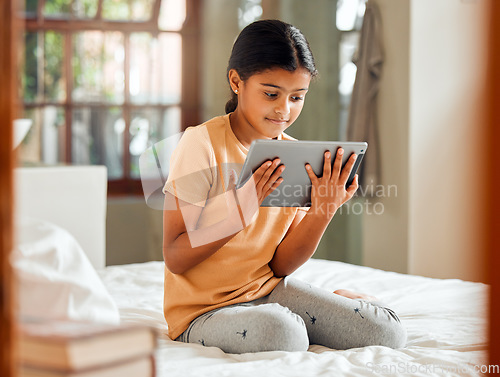 Image of Little girl, tablet and smile on bed for entertainment, education or learning while relaxing at home. Happy female child enjoying time streaming holding touchscreen for online elearning in bedroom
