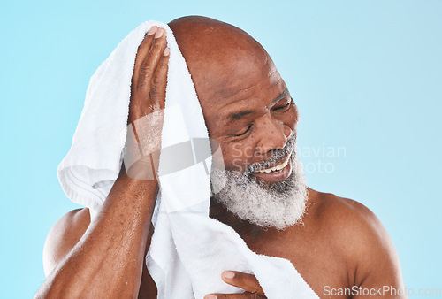 Image of Shower, senior man and towel for cleaning, cosmetics and hygiene against blue studio background. Black male, mature guy and cloth for skincare, dry and spa body care for beauty, retirement and luxury