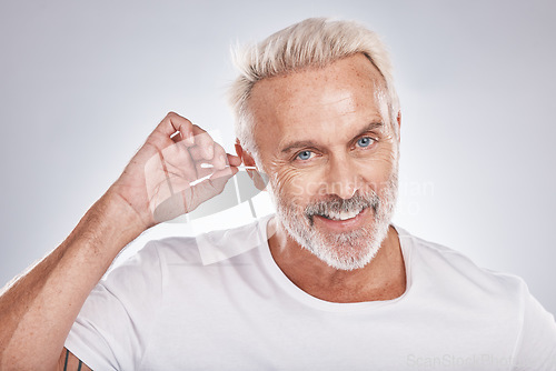 Image of Senior man, cotton bud and ear cleaning or happy portrait in white studio background for grooming hygiene, wellness and wax removal. Elderly model, cosmetics ears cleaner and body care happiness