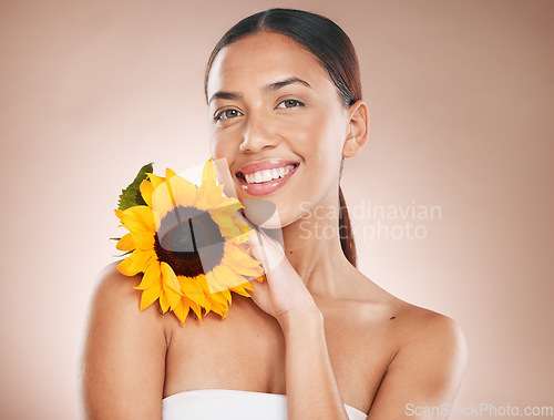 Image of Beauty, skincare and flower with portrait of woman for natural, cosmetics and organic facial product. Spring, sunflower and smile with face of girl model for self care, luxury and wellness in studio