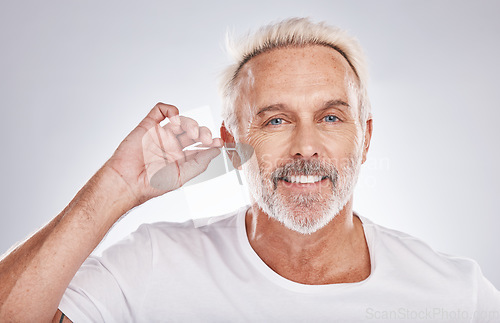 Image of Senior man, cotton bud and ear cleaning happy portrait in white studio background for grooming hygiene, healthy wellness and wax removal. Elderly model, cosmetics ears cleaner and body care happiness