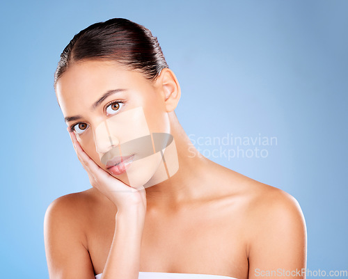 Image of Face portrait, skincare and beauty of woman in studio on a blue background. Hands, natural cosmetics and makeup of young female model with healthy, smooth and glowing skin after facial treatment.