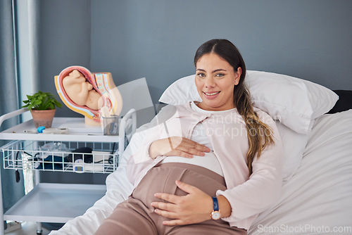 Image of Pregnant woman, doctor consultation office and portrait of a new mother ready for ultrasound. Hospital bed, medical clinic and mama smile with happiness hold her stomach at a healthcare consultation