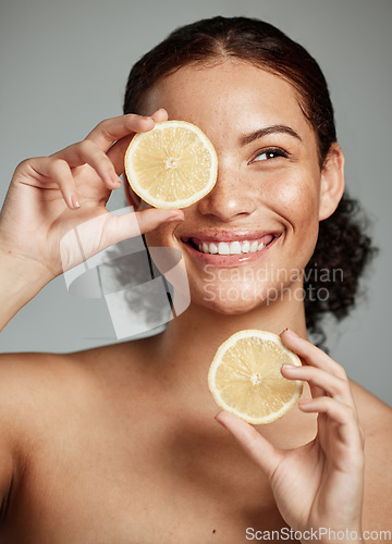 Image of Face, skincare and woman with lemon in studio isolated on a gray background. Fruit, organic cosmetics and happy female model holding lemons for healthy diet, vitamin c or minerals, wellness or beauty