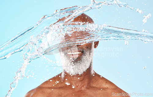 Image of Happy black man, face and water splash in studio for cleaning, self care and headshot cosmetics on blue background. Shower, wellness and male beauty with water drops, healthy skincare and facial body