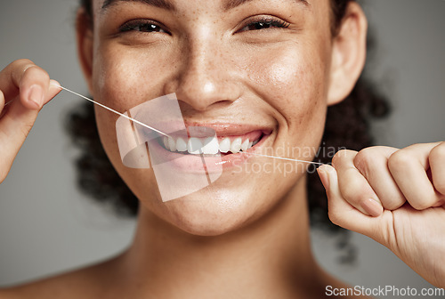 Image of Woman portrait, dental floss and flossing teeth with smile for oral hygiene, health and wellness on studio background. Face of female happy about self care, healthcare and grooming for healthy mouth