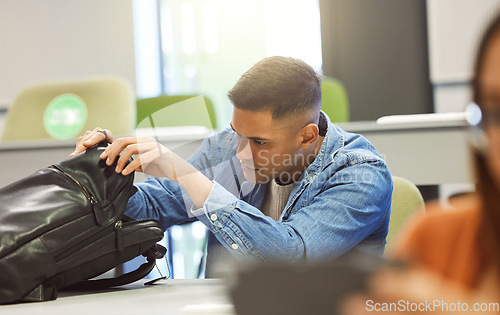 Image of University student, man and backpack in a classroom for education, studying and learning at campus. Person in class searching for object in bag to learn and study at college, school or campus