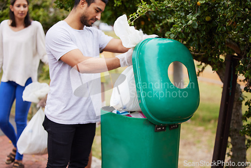 Image of Volunteer cleaning, garbage bin and man throw trash, pollution or waste product for environment support. Community help, NGO charity and eco friendly people helping with nature park plastic clean up