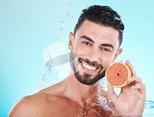 Image of Skincare, water splash and portrait of man with grapefruit on blue background for vitamin c detox for healthy skin and smile. Fruit, water and facial wellness, spacleaning and happy male model face