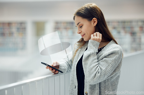 Image of Woman, phone and smile for social media, networking or chatting in communication at a library. Happy female smiling for texting, research or browsing for books on smartphone at big book store or mall