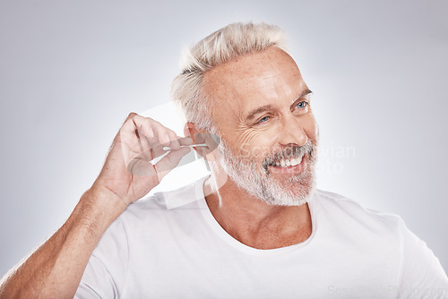 Image of Elderly man, ear cleaning with cotton swab for hygiene, grooming and clean body with cosmetic care against studio background. Beauty, health and wellness, senior male and happy with natural cosmetics