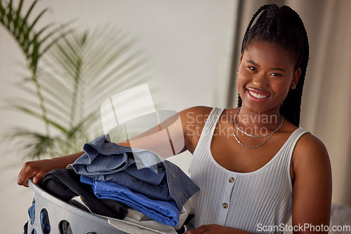 Image of Laundry, basket and portrait of black woman with clothes folded, housekeeping and smile in living room. Happiness, cleaning and washing, happy modern housewife doing household chores in Atlanta home.
