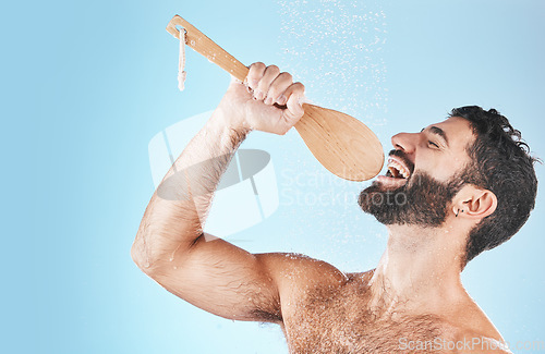 Image of Bathroom, singing and washing with a man model in studio on a blue background using a loofah to sing. Water, showering and hygiene with a handsome male wet while cleaning for personal body care