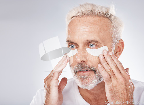 Image of Skincare, eyes patch and man in studio for dermatology facial, face cosmetics or collagen mask advertising or marketing mockup. Senior model, hands application and eye patches or anti aging product
