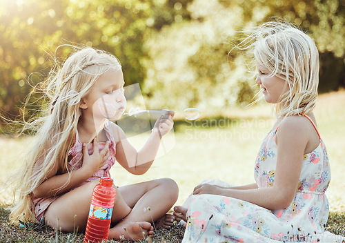 Image of Nature, girls and friends blowing bubbles in a green garden being playful, happy and fun together. Happiness, holiday and sisters playing on the grass in an outdoor park in summer in Australia.