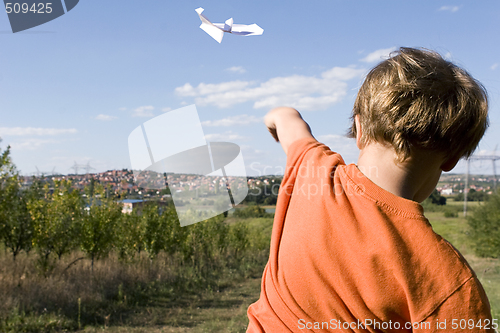 Image of young boy flying a paper plane